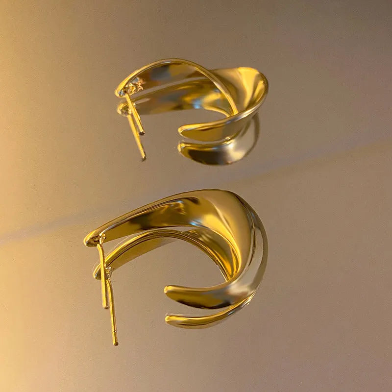 Gold twisted geometric metal earrings with round design elements