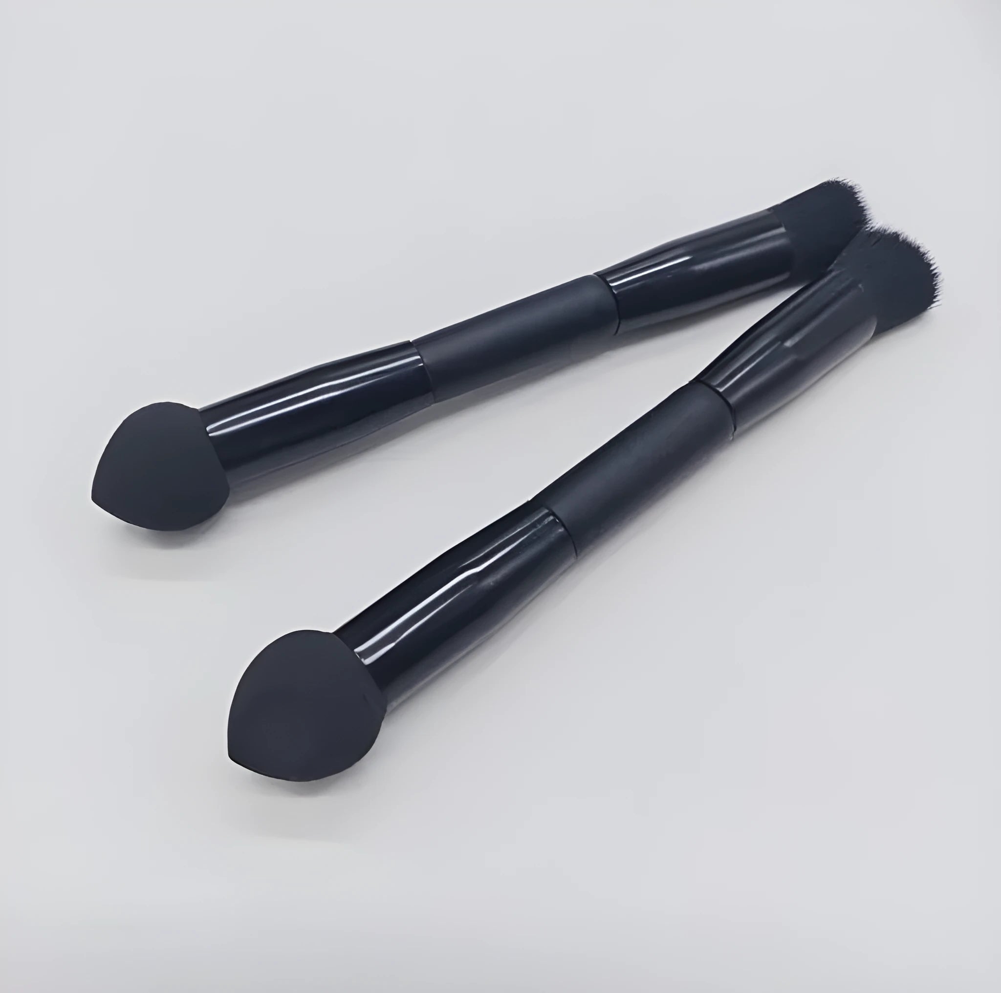 Double-headed black makeup brush with angled sponge and concealer brush on wooden handle