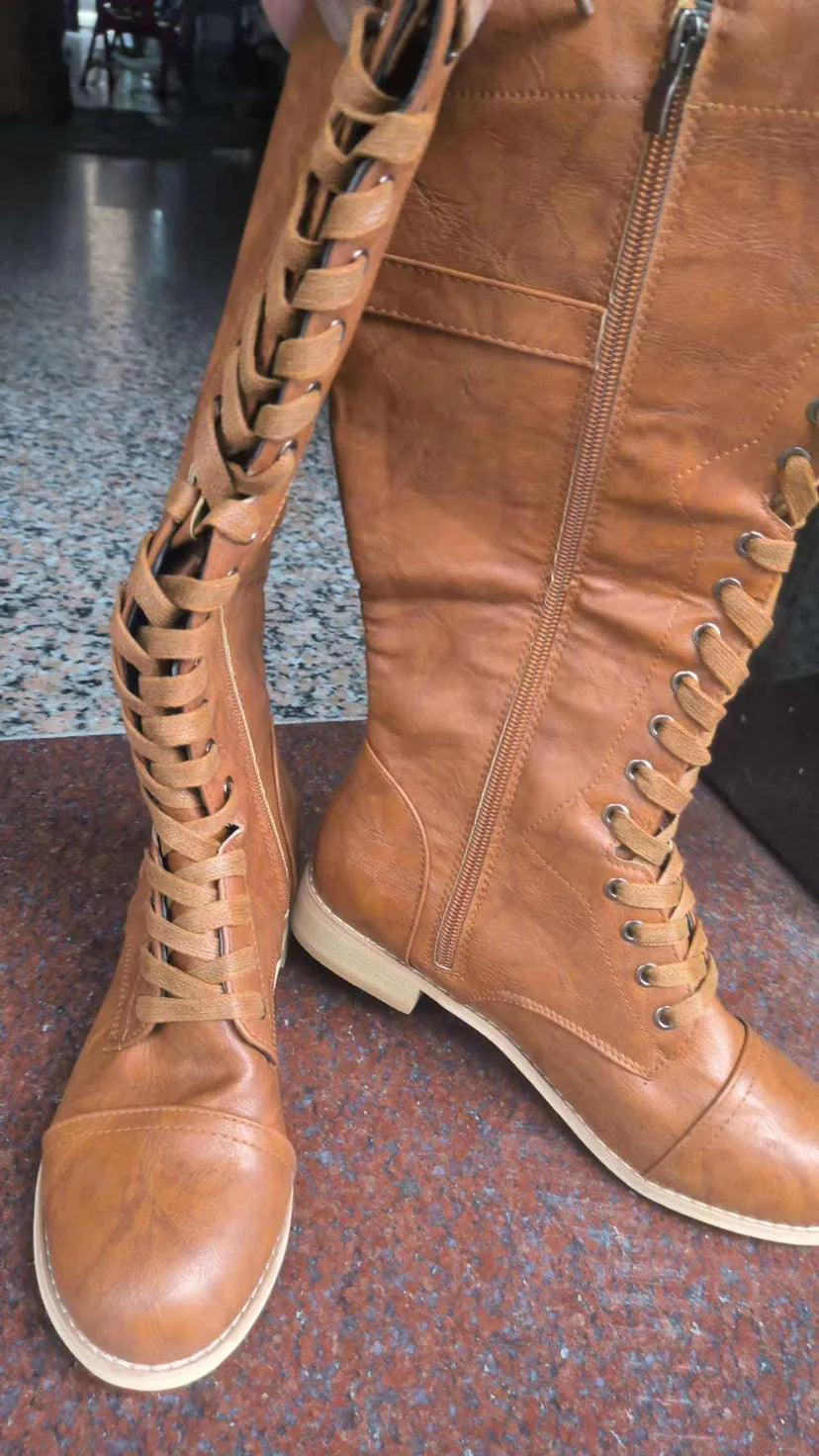 Women's black knee-high boots with cross strap design and knight boot styling