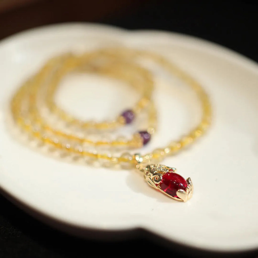 Handmade gold and ruby quartz bracelet with a chopstick charm on a wrist.