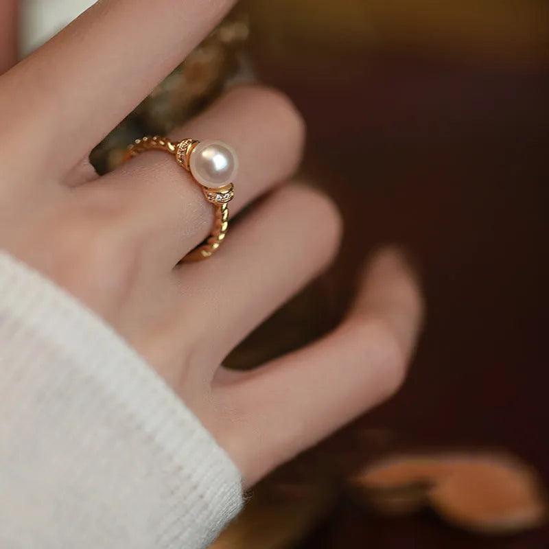Adjustable antique-style copper ring with a geometric shape and an inlaid pearl, shown in gold and silver colour options.