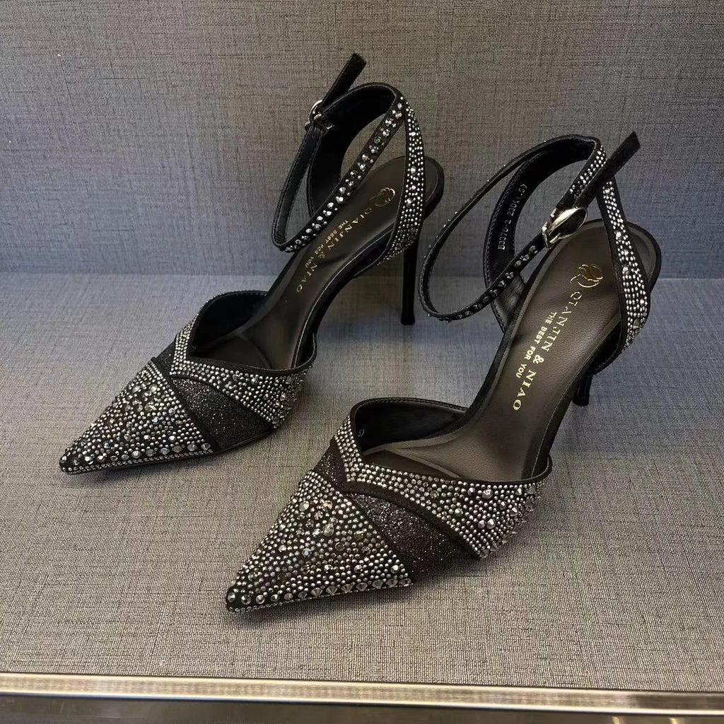 Women's black high heel shoe with pointed toe, stiletto heel, red sole, and hollow design detail.