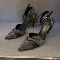 Women's black high heel shoe with pointed toe, stiletto heel, red sole, and hollow design detail.