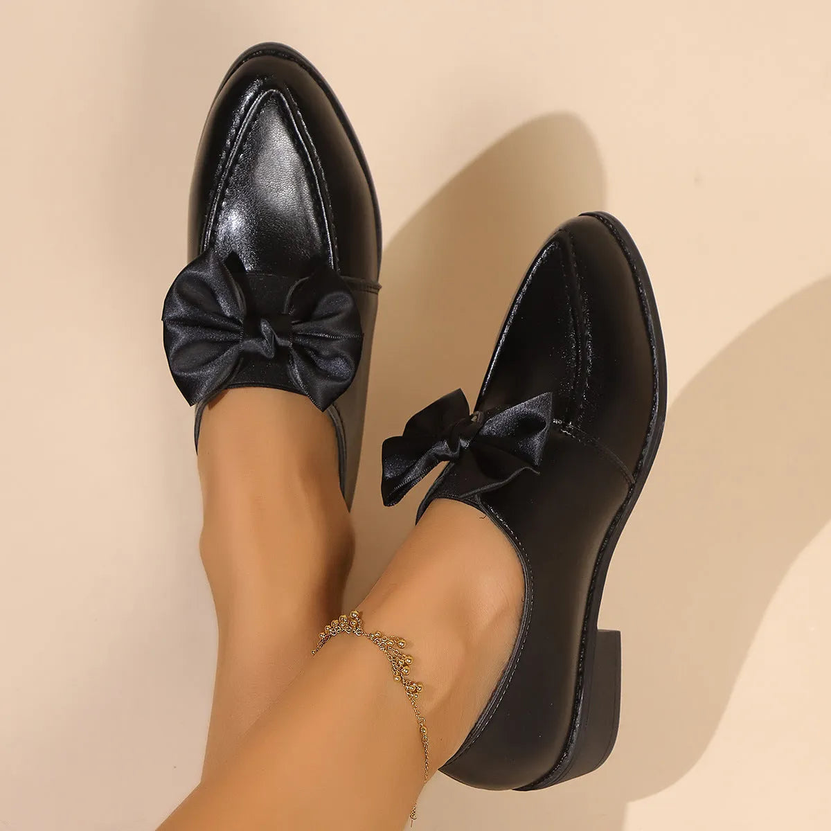 Women's leather-look slip-on shoes with decorative bow buckle detail and pointed toe