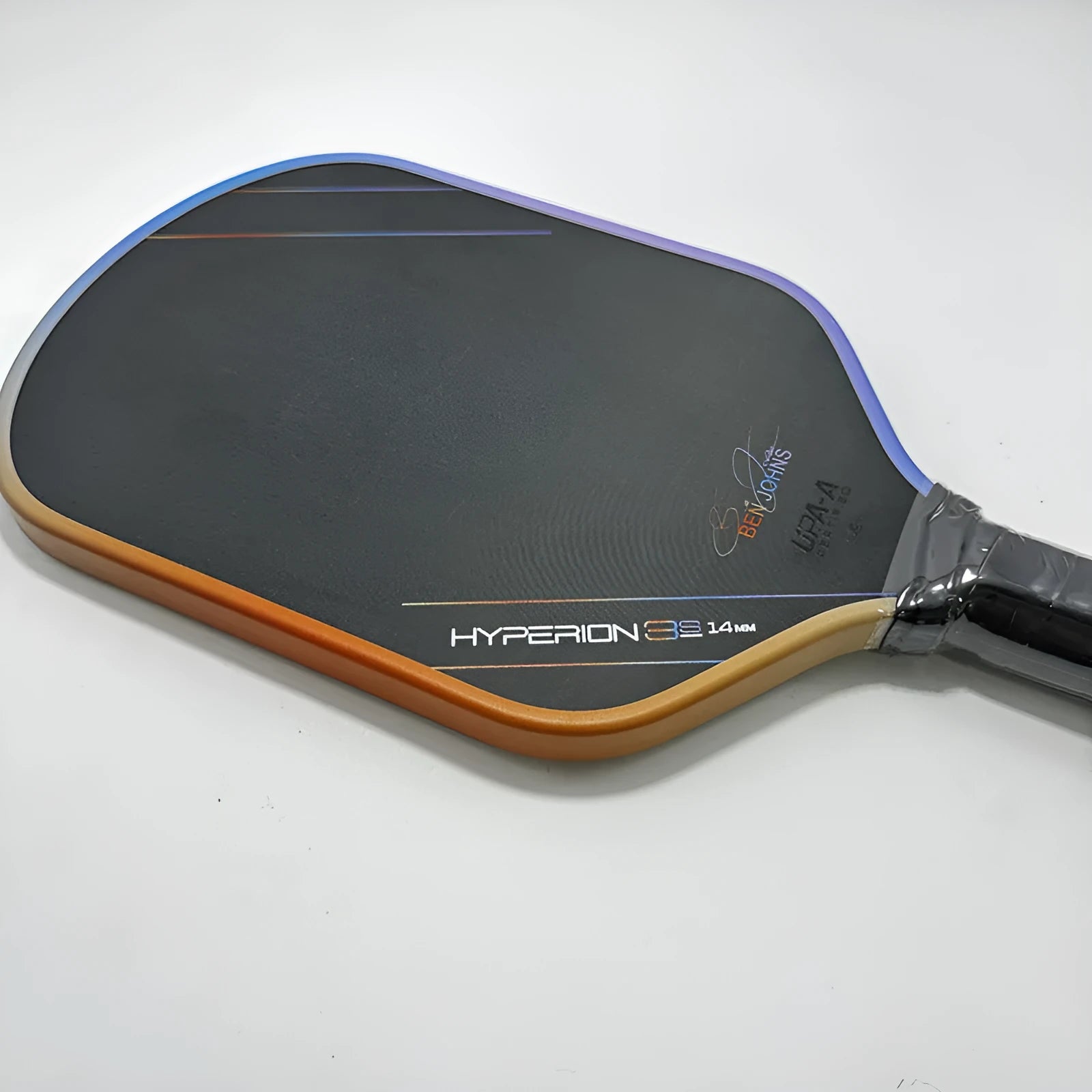 Matte black pickleball racket with Teflon cloth pattern, showing carbon fibre construction and honeycomb core.