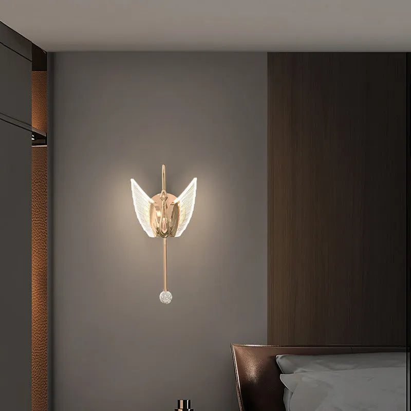 Modern gold swan-shaped wall lamp with acrylic shade mounted beside bed