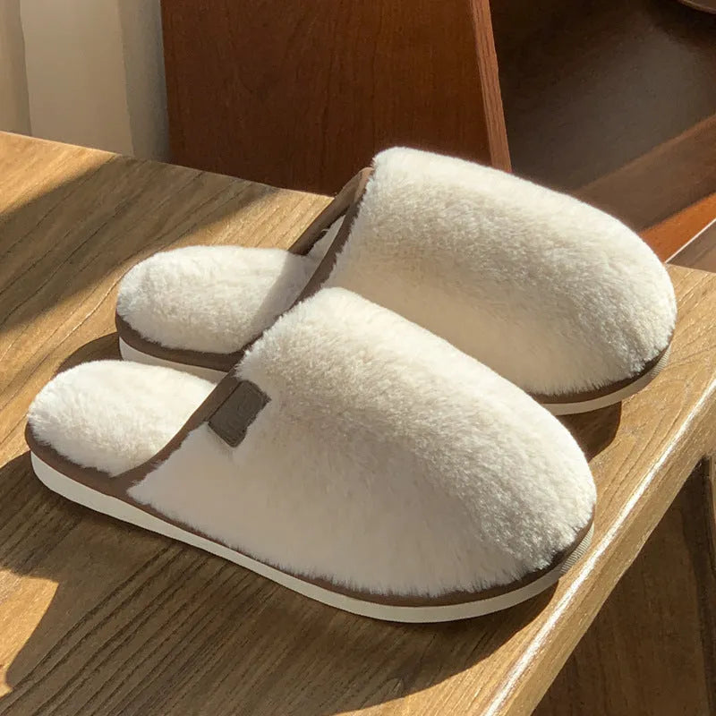 Solid colour winter plush slippers with non-slip PVC sole on a wooden floor.