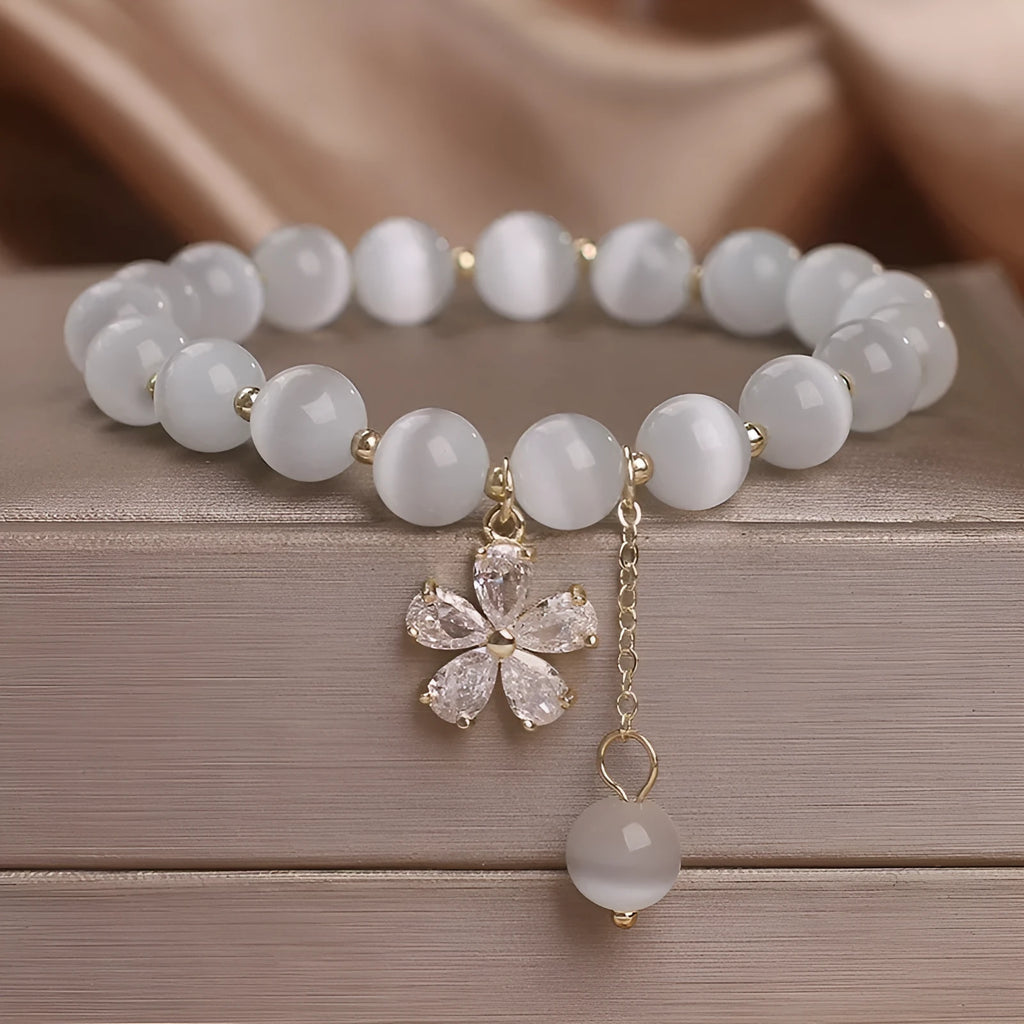 Women's white cat's eye stone bracelet with floral tassel and safety buckle clasp.