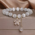 Women's white cat's eye stone bracelet with floral tassel and safety buckle clasp.