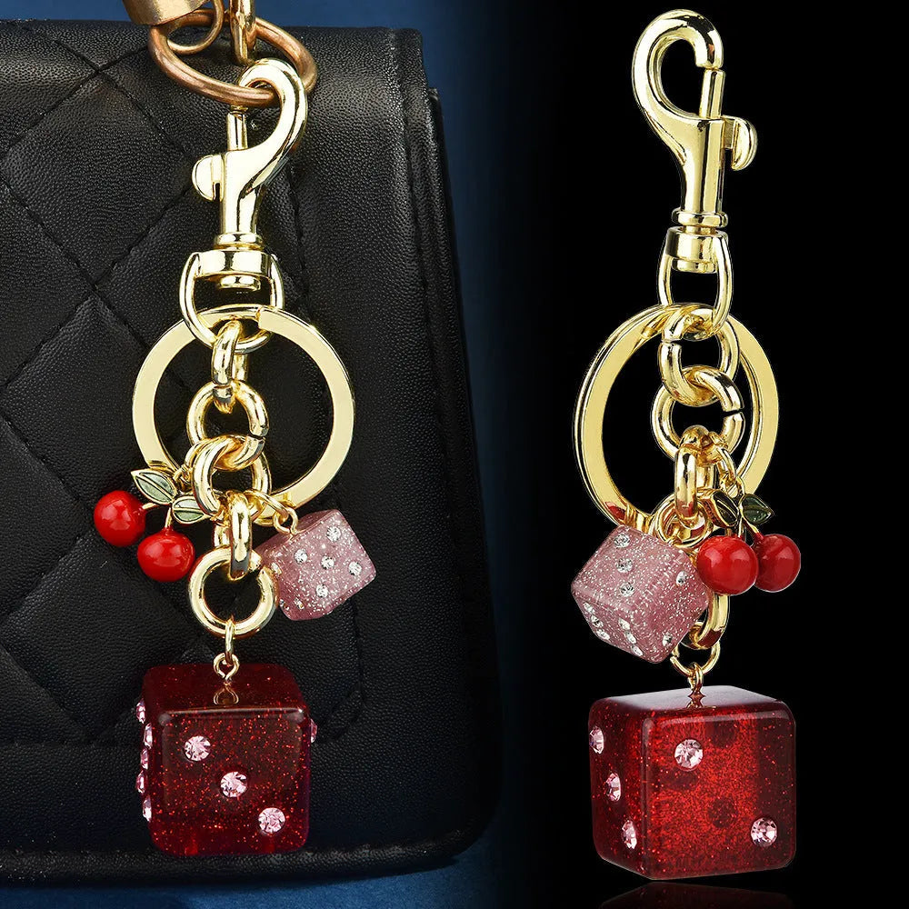Close-up of a square metal keychain pendant with a vintage cherry two-tone dice pattern.