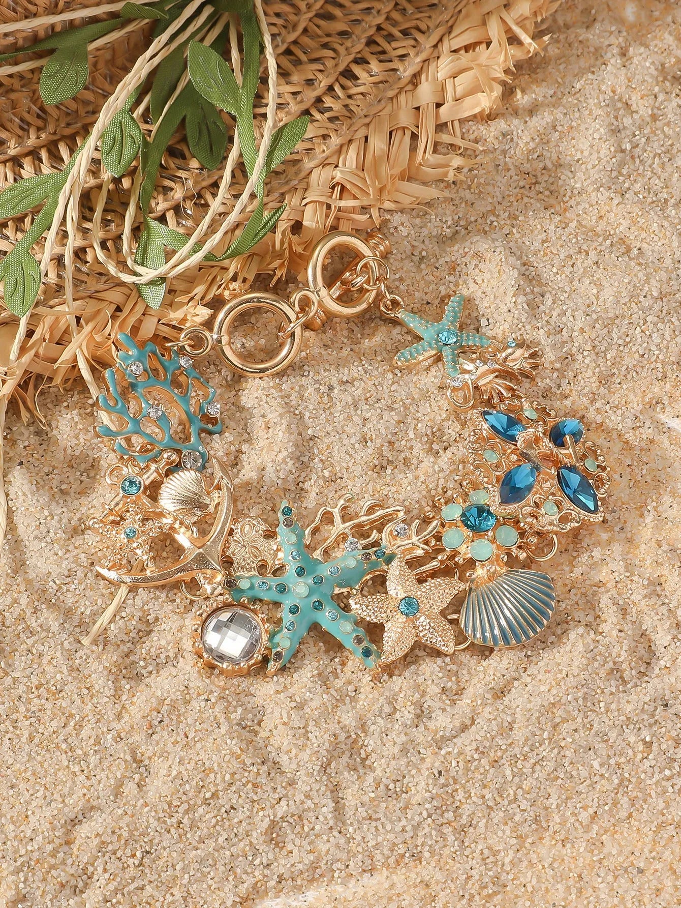 Alloy starfish bracelet with blue coral rhinestone boat anchor charm on a wrist.