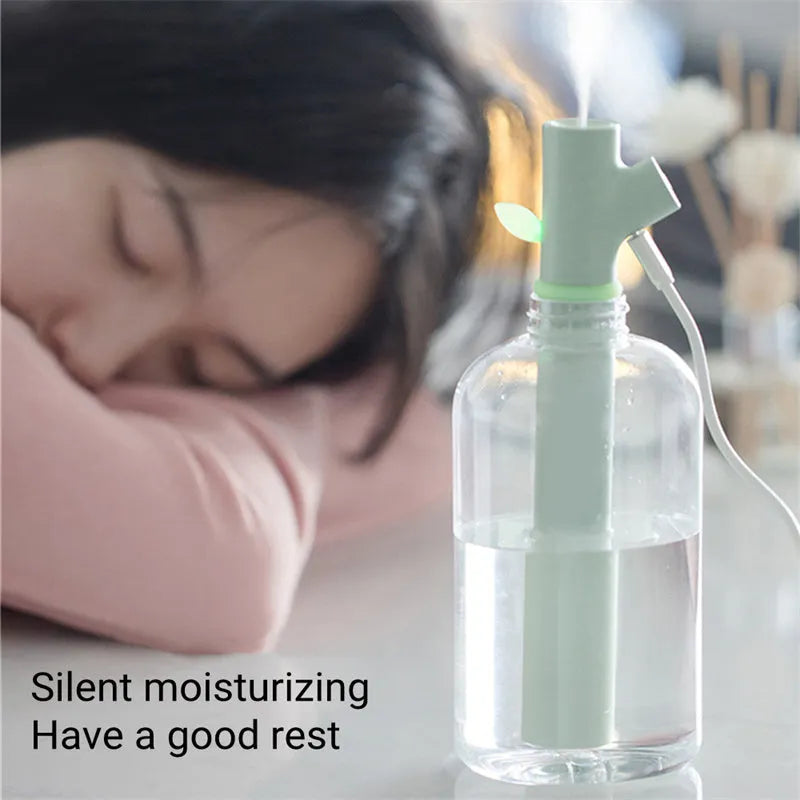 Transparent plastic mini USB branch humidifier on desk with mist output