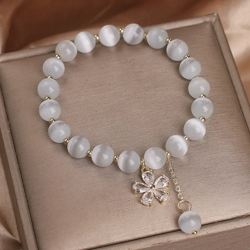 Women's white cat's eye stone bracelet with floral tassel and safety buckle clasp.