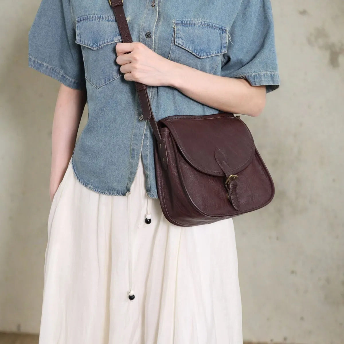 Genuine leather messenger bag with shell shape and sewing line detail in brown
