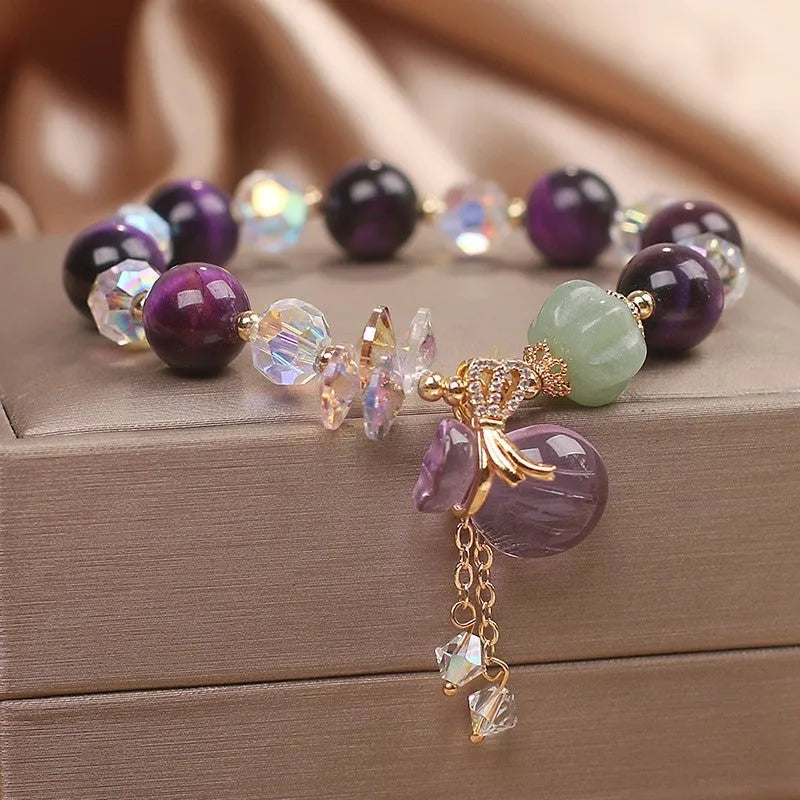 Women's crystal bracelet with purple Tigereye money bag pendant and clear rhinestone accents