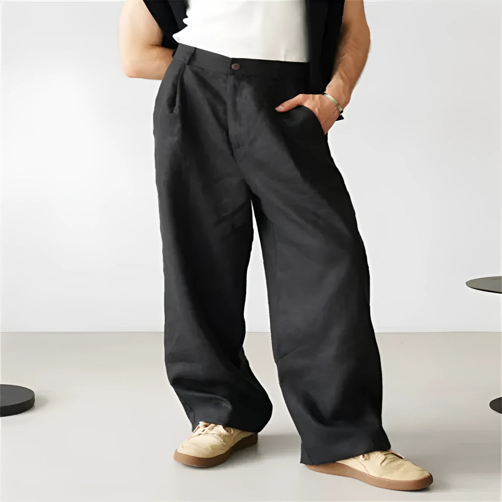 Men's loose linen pleated high waist jogger pants in black, side view showing straight-leg cut and zipper fly