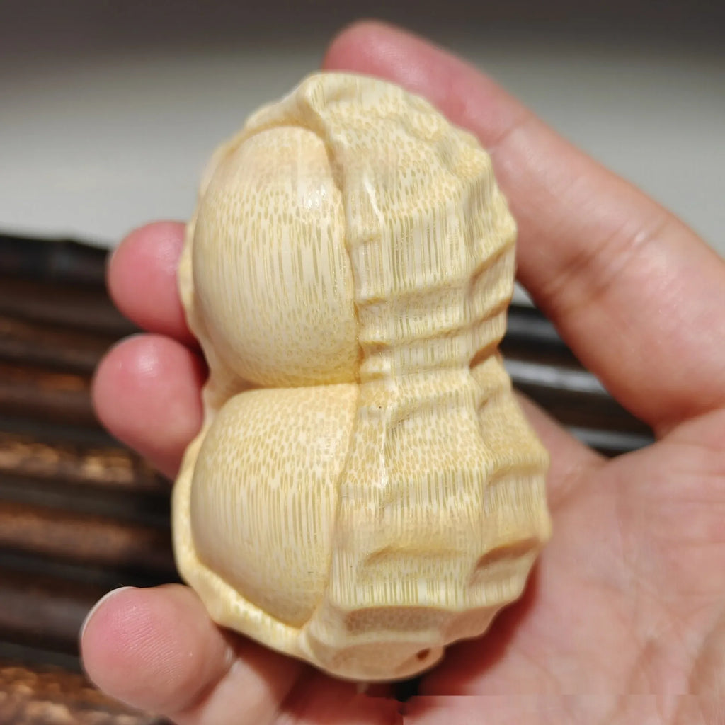Solid natural bamboo ornament carved into a peanut shape on a wooden surface.