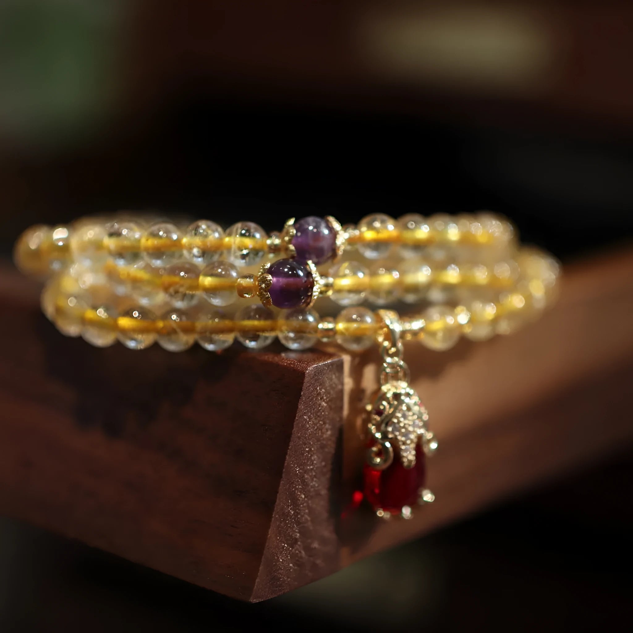 Handmade gold and ruby quartz bracelet with a chopstick charm on a wrist.