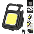 Black aluminium alloy COB keychain flashlight on a metal surface, magnetic base attached, 6x4.2cm size, with foldable handle extended