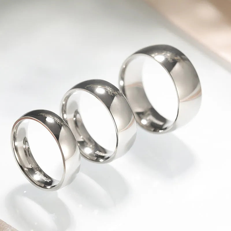 Silver titanium steel unisex ring on a finger, showing minimalist band in 2mm, 4mm, and 6mm width options.