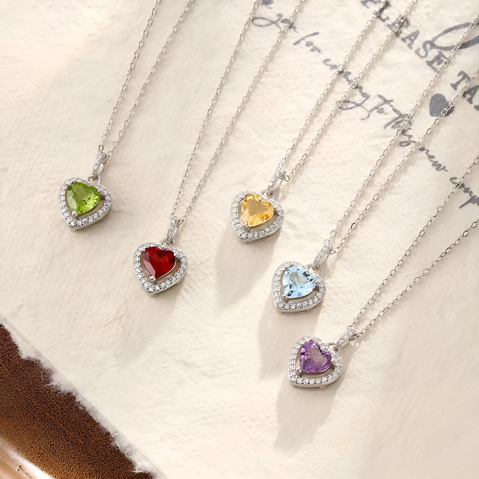 Women's sterling silver heart pendant necklace with a coloured gemstone on an adjustable chain.