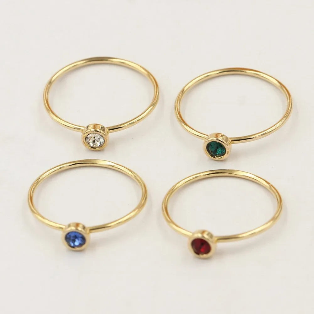 Gold-plated women's knuckle ring with clear stones in green, blue, red, or white on a copper band.