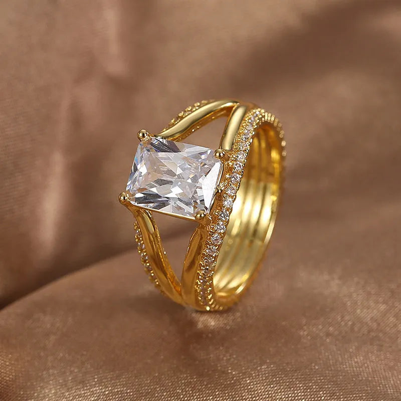Gold geometric women's ring with a square zircon stone on a hand.