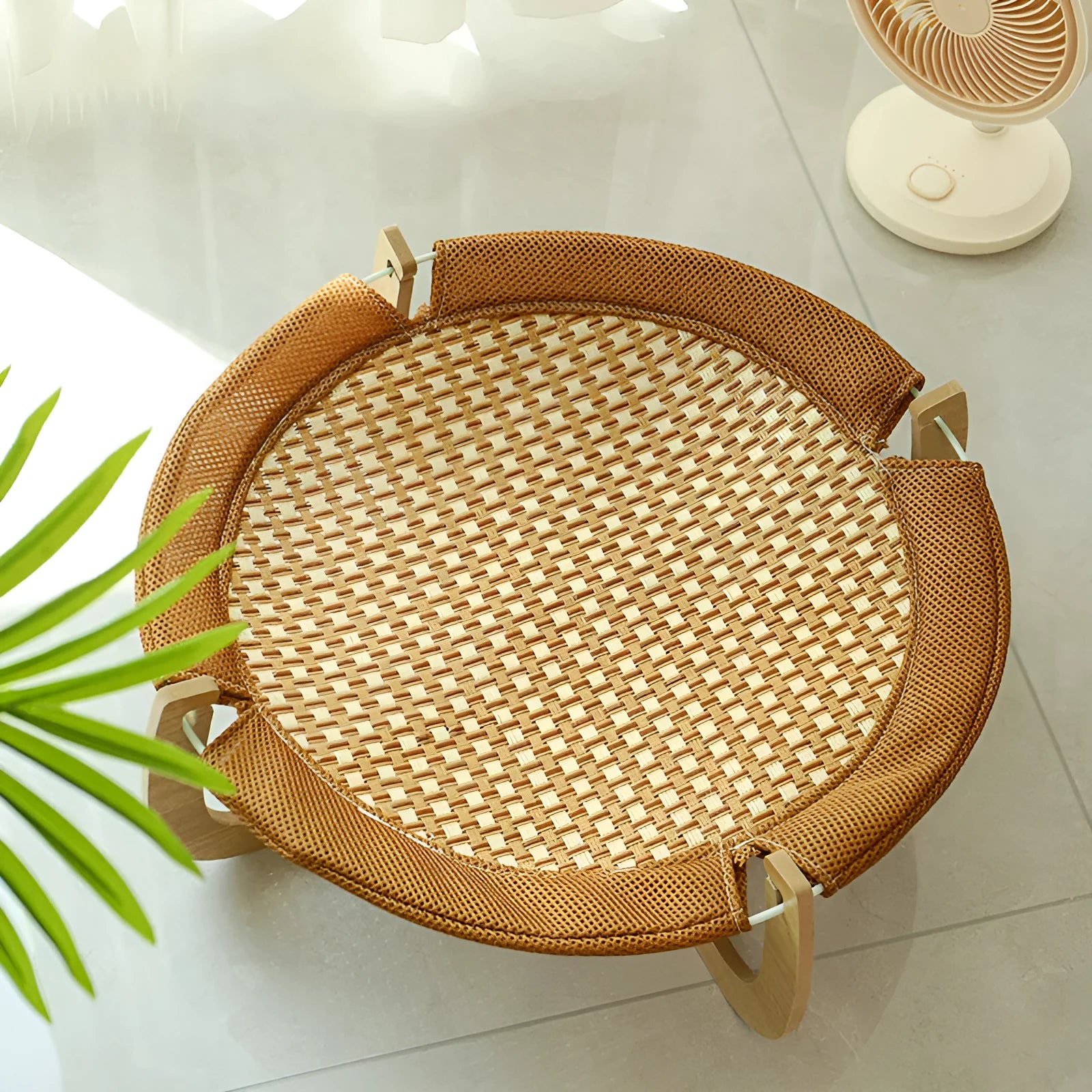 Brown woven rattan pet hammock bed for cats and dogs on a cool mat.