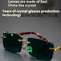 A pair of frameless rectangular sunglasses with dark green crystal lenses, a case, and a lens cloth.