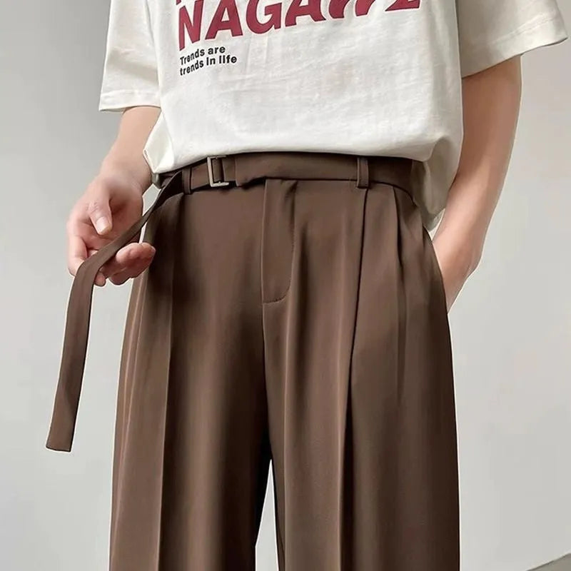 A pair of thin, straight-cut wide leg trousers in black on a hanger.
