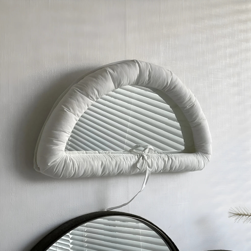 Soft cotton-filled fabric mirror in solid colour hanging as a background prop