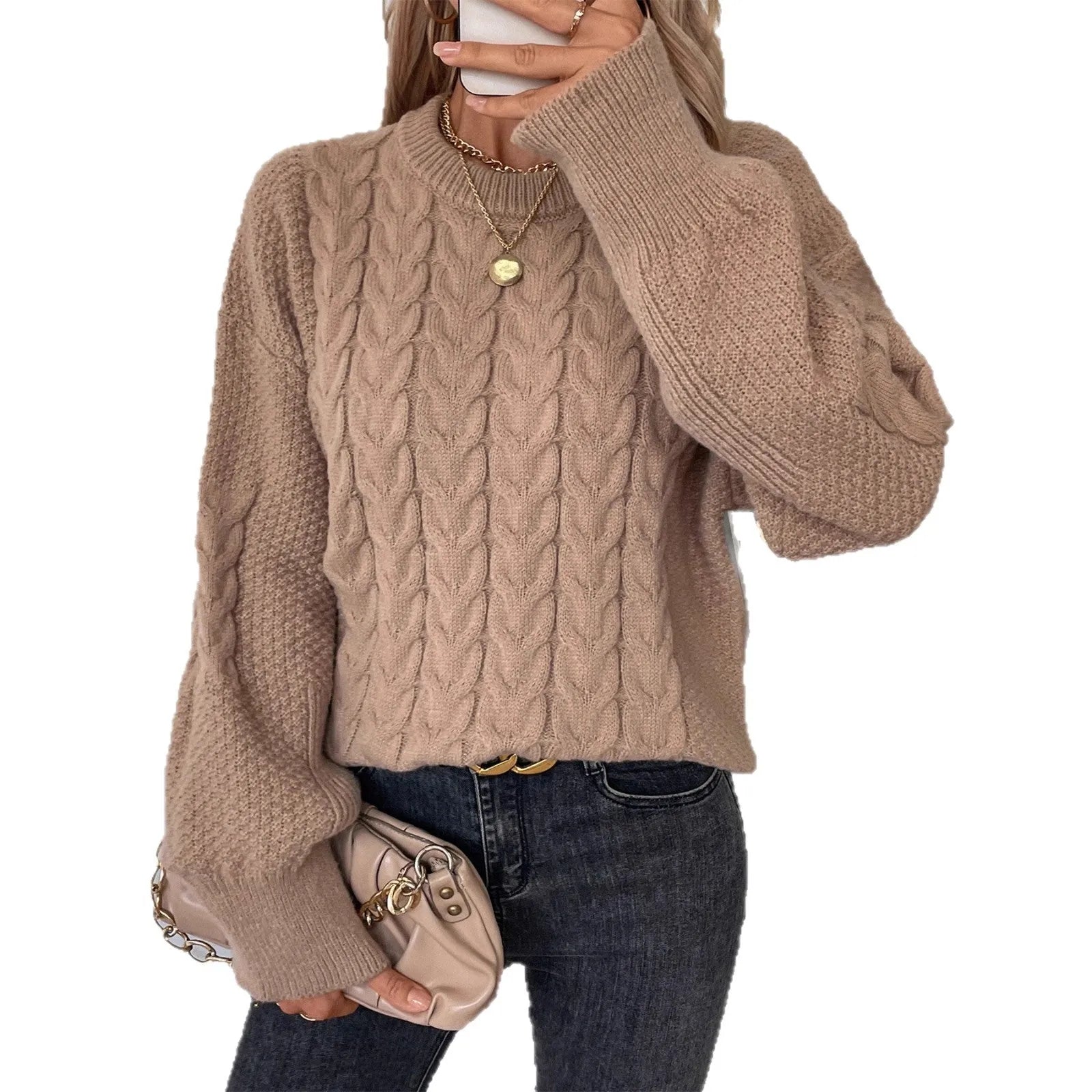Woman wearing a loose beige round neck sweater with a twisted knit texture detail on the front.