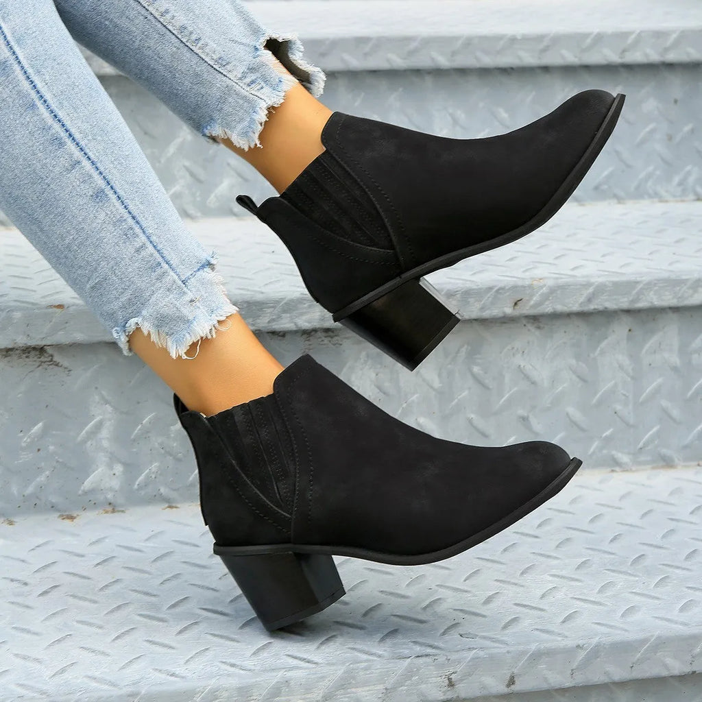 Black women's pointed toe ankle boots with a thick square low heel and slip-on design.