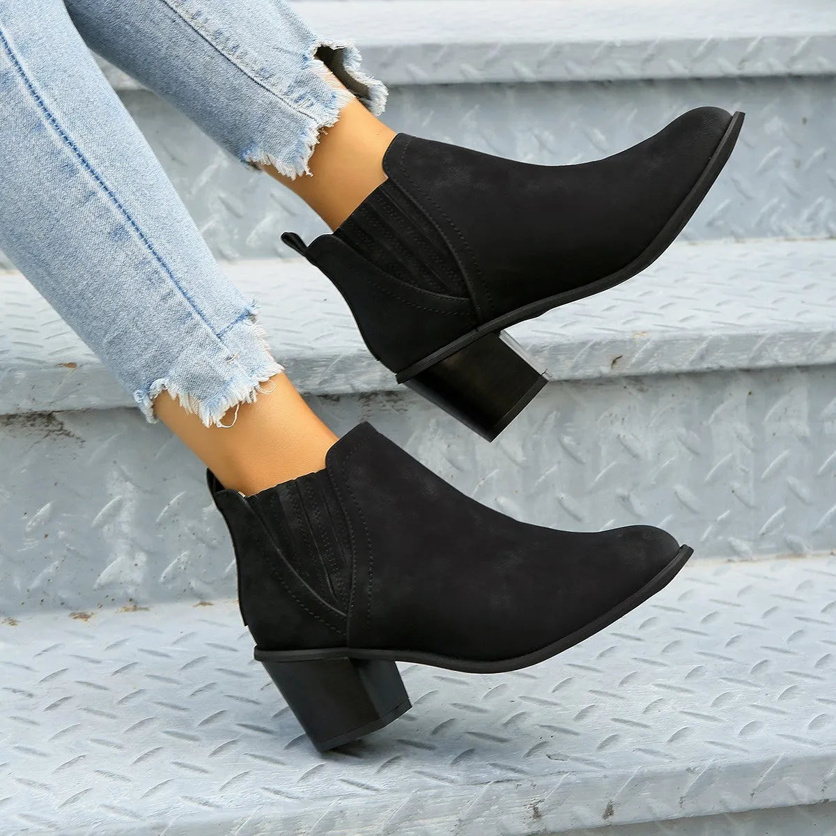 Black women's pointed toe ankle boots with a thick square low heel and slip-on design.