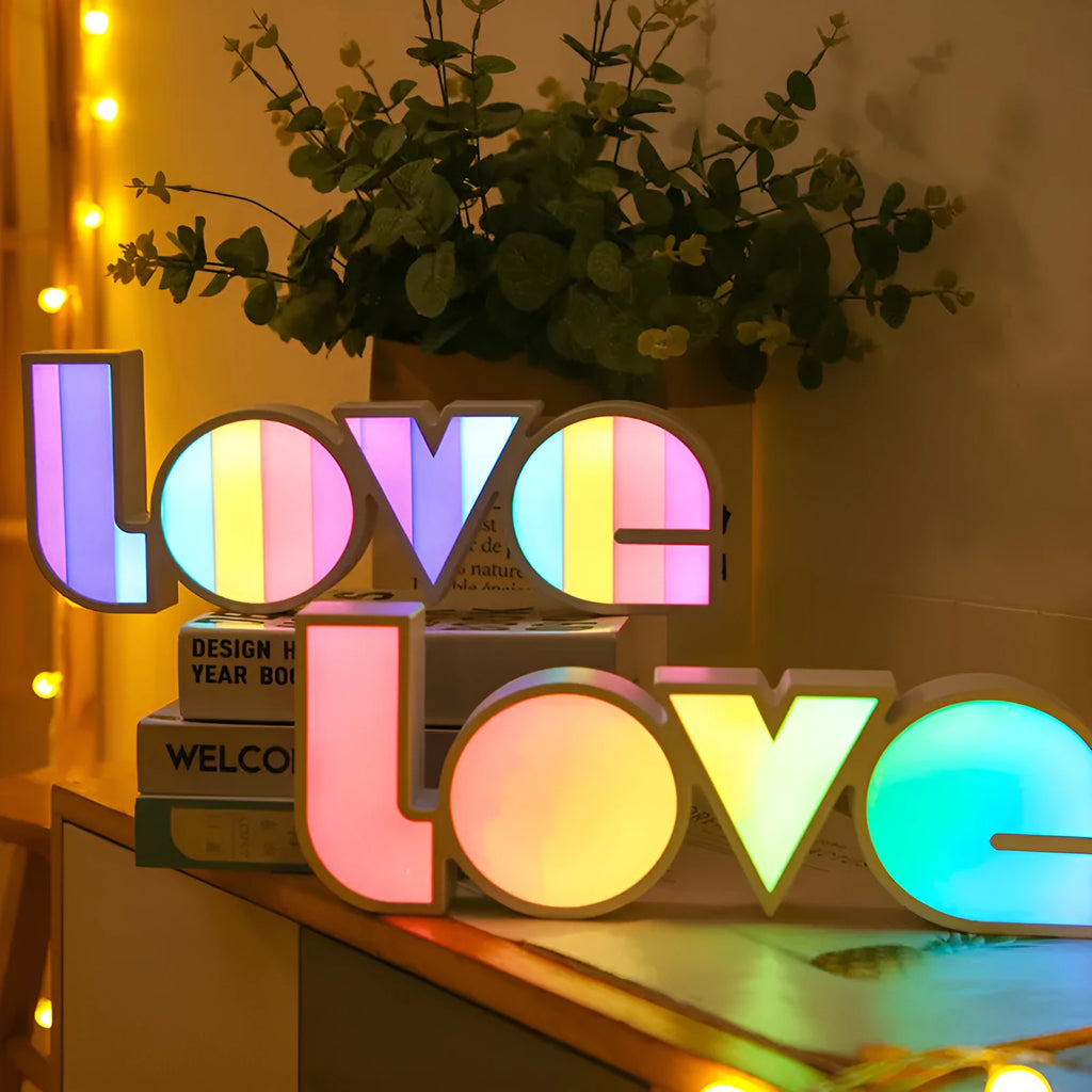 LED LOVE light with rainbow lampshade on a table against a dark background