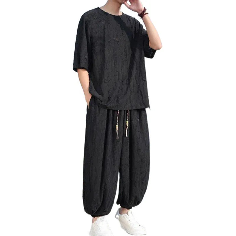 Men's thin short-sleeved loose two-piece knitwear suit in black on model, with cropped trousers