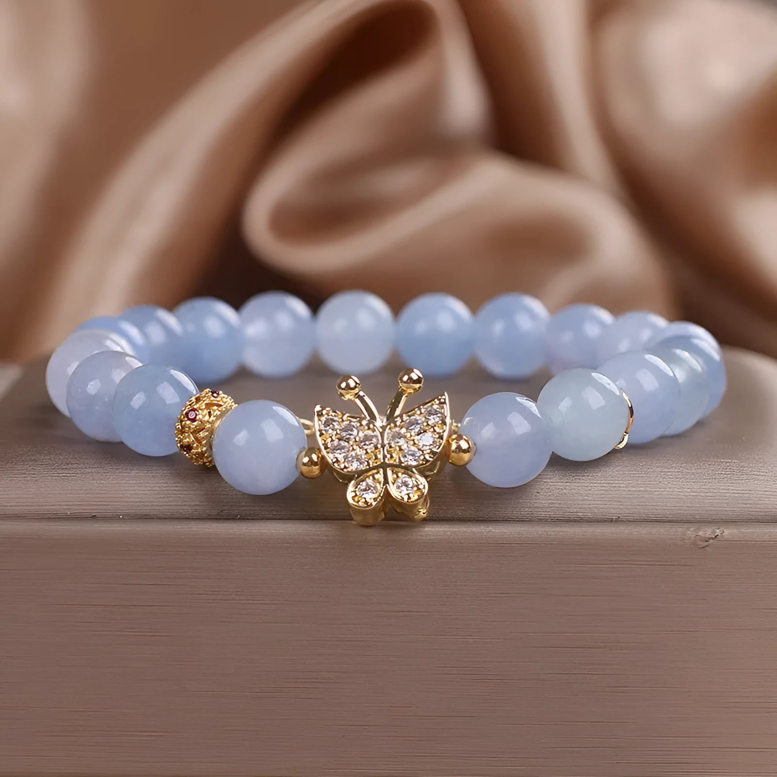 Sky blue crystal butterfly stretch bracelet for women with pearl and rhinestone accents on a plain background