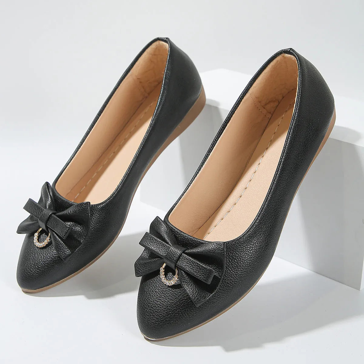 Women's beige casual flat loafers with a bowknot on the front, showing the shallow mouth and rubber sole.