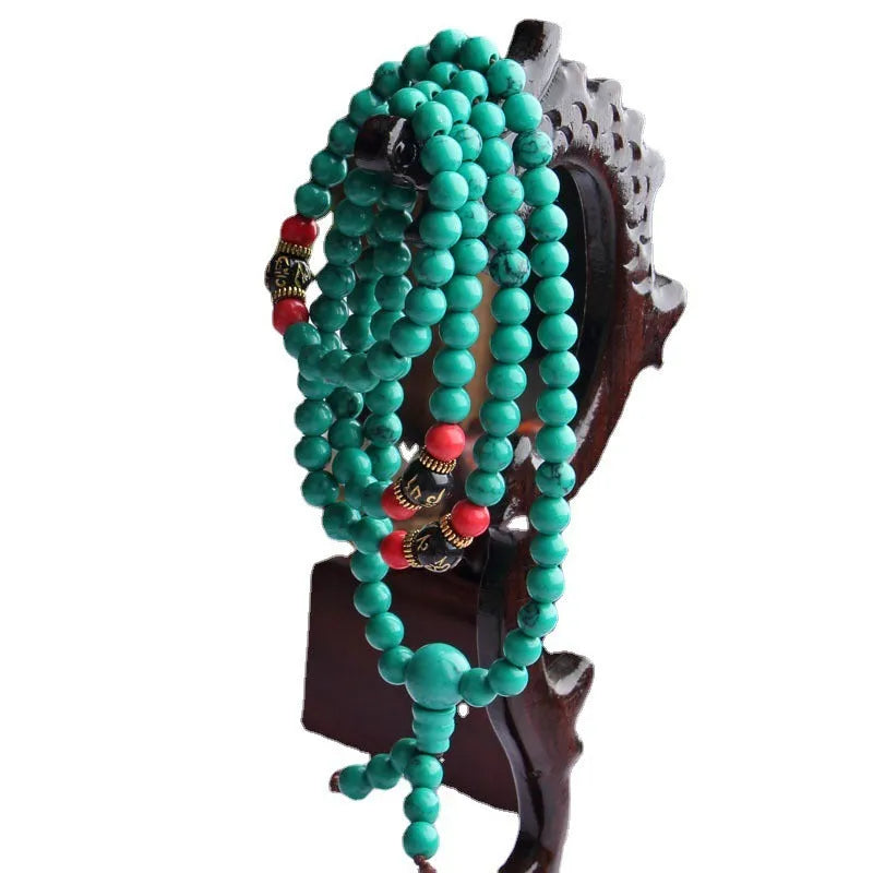 Multi-layer turquoise bracelet with 108 round polished beads in 6mm size on plain background