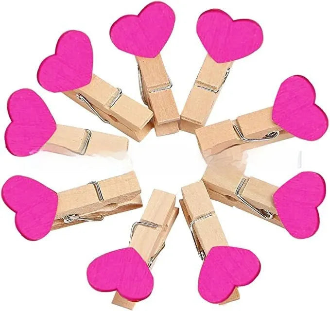 Five wooden heart-shaped clips in different colours on wooden surface