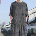 Men's thin short-sleeved loose two-piece knitwear suit in black on model, with cropped trousers