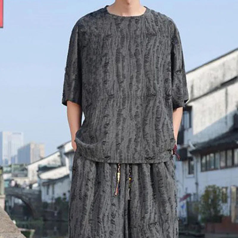 Men's thin short-sleeved loose two-piece knitwear suit in black on model, with cropped trousers