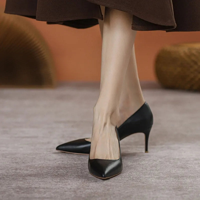 Black pointed high heel shoes with stiletto heel and microfiber upper on a white background