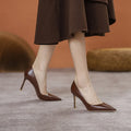 Black pointed high heel shoes with stiletto heel and microfiber upper on a white background