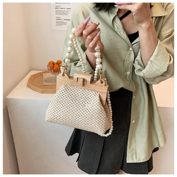 Women's woven straw shoulder bag with pearl chain detailing and multiple interior compartments