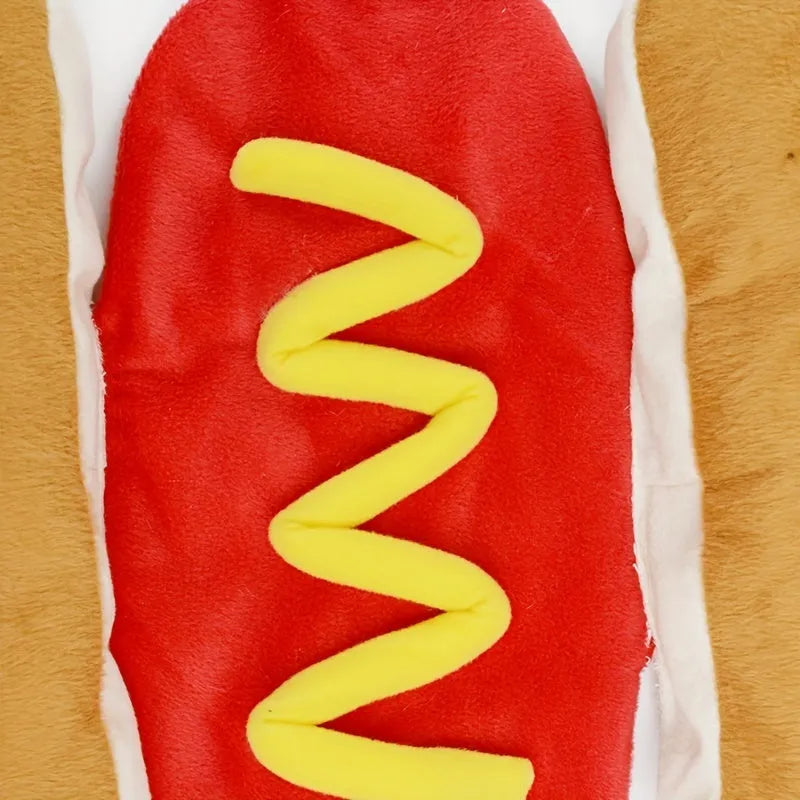 A small dog wearing a brown and beige plush hot dog costume with openings for head, legs, and tail.