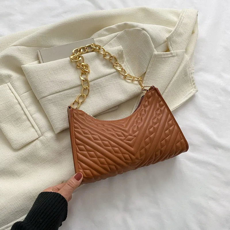 Black pleated chain baguette shoulder bag with adjustable strap and soft handle on white background