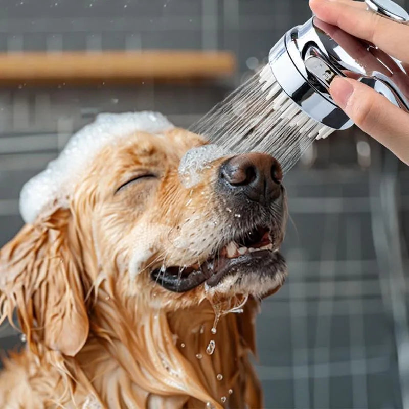 Silver dog shower attachment with soft silicone comb teeth and ergonomic grip on a white background