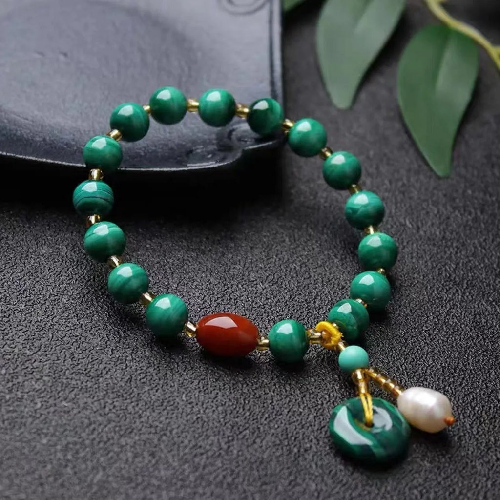 Handmade natural malachite and red agate barrel bead bracelet on a wrist, showing green and red stone details.