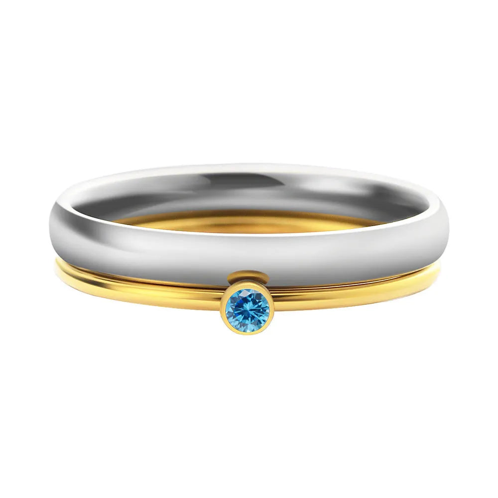 December birthstone ring in titanium steel with geometric engraving and gold accents on a grey background.